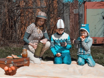 a mother and kids on a picnic blanket