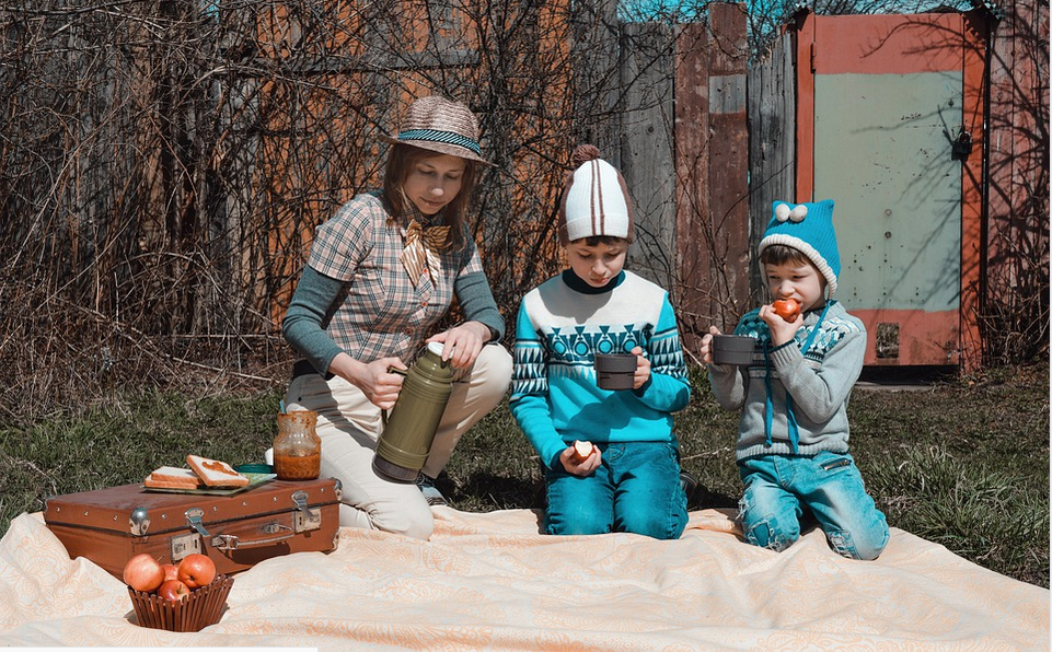 a mother and kids on a picnic blanket